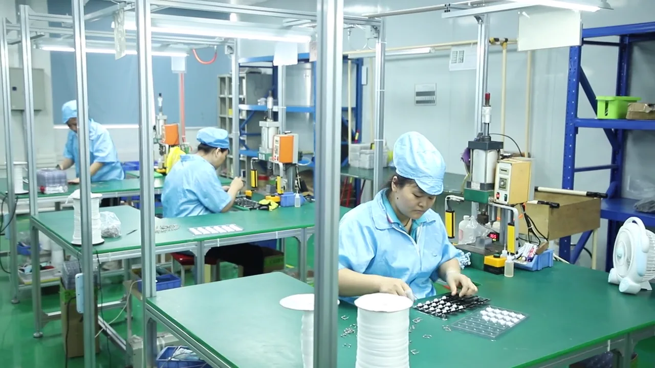 AIMEI operator assembling personal care device components at a production workstation.